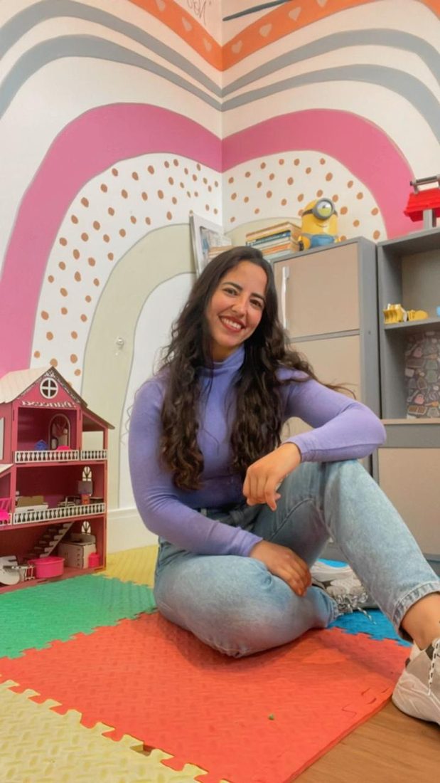 Lara Lyss sentada no chão da sala de atendimento infantil